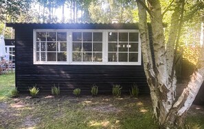 Cozy cabin surrounded by lush greenery and a tree.