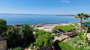 A coastal view with a clear sky, rocky shoreline, and lush greenery. - VILLA THE HELM - ORTIGIA HOLIDAYS (Fontane Bianche)
