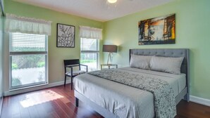 A bedroom with a bed, a chair, a ceiling fan, and artwork on the walls. - Home Close to Saint Pete Pier new Spacious (St. Petersburg)