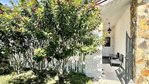 A patio area with a stone wall, a white door, and a table with chairs. - Home Close to Saint Pete Pier new Spacious (St. Petersburg)
