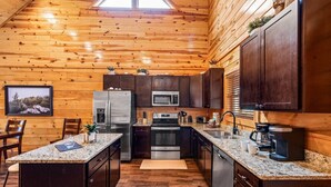 Eine Küchenzeile im Blockhausstil mit Holzwänden, Granit-Arbeitsplatten, Edelstahlgeräten und einem Essbereich mit Tisch und Stühlen.