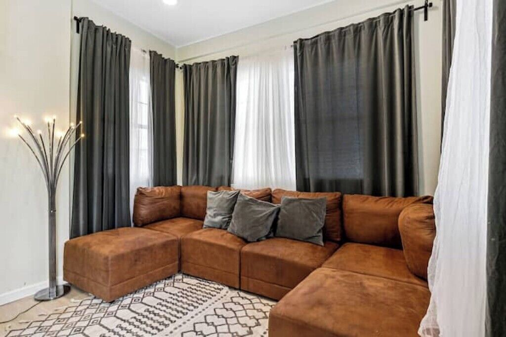 A living room with a brown sectional sofa, a patterned rug, and a tall floor lamp.