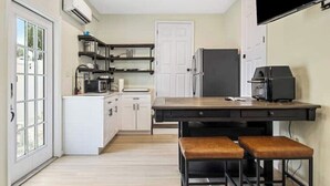 A compact kitchen with a central island, white cabinetry, and a black refrigerator.