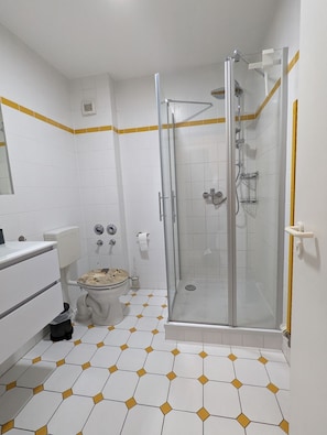 A bathroom with a glass-enclosed shower, a toilet, and a sink.