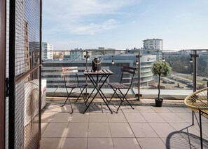 A balcony with a table and chairs, a potted plant, and a view of the cityscape. - Ochota City View Stylish Studio (Warszawa)