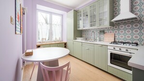 A kitchen with green cabinets, a white stove, and a window with a view of trees. - Metro Młynów Colourful Apartment (Warszawa)
