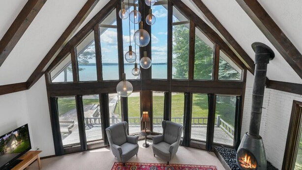 Ein Zimmer mit hohen Decken, großen Fenstern, einem Kamin und zwei Sesseln.