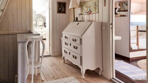 A room with wooden walls and a white dresser with drawers. There is a chair and a table with a lamp. - Nice home in Nösund with house sea view (Nösund)