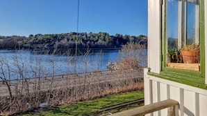 A lakeside view from a building with a wooden deck and a window with a potted plant. - Nice home in Nösund with house sea view (Nösund)