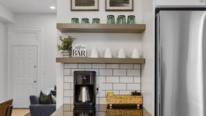 A modern kitchen with white cabinetry, a stainless steel refrigerator, and a coffee bar with mugs and jars. - 3BR Historic St. Charles, MO-Walking distance to Main Street (Saint Charles)