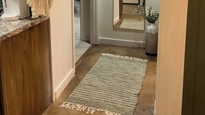 A hallway with a macrame wall hanging, a kitchen area with a coffee maker, and a refrigerator. - Cozy Home on the edge of Rolla! (Rolla)