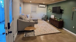 A living room with a wooden ceiling, a grey sofa, a coffee table, and a TV on the wall. - Cozy Home on the edge of Rolla! (Rolla)
