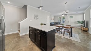 A modern kitchen with a central island, built-in appliances, and a dining area with a wooden table and chairs. - Entire Cozy Duplex Ideal for Families & Groups (Memphis)