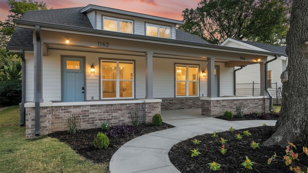 A two-story house with a brick foundation and a covered porch. - Entire Cozy Duplex Ideal for Families & Groups (Memphis)