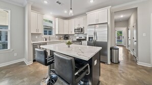 A modern kitchen with white cabinets, stainless steel appliances, a marble island, and a bar seating area. - Entire Cozy Duplex Ideal for Families & Groups (Memphis)