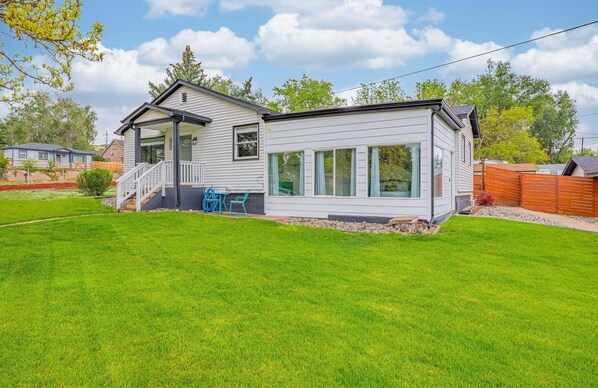 A two-story mobile home with a porch, a small deck, and a well-maintained lawn.