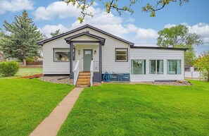 A two-story house with a front porch, a small deck, and a well-maintained lawn.