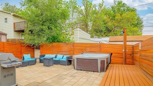 Ein Garten mit Holzterrasse, Gartenmöbeln, Whirlpool und Grill.