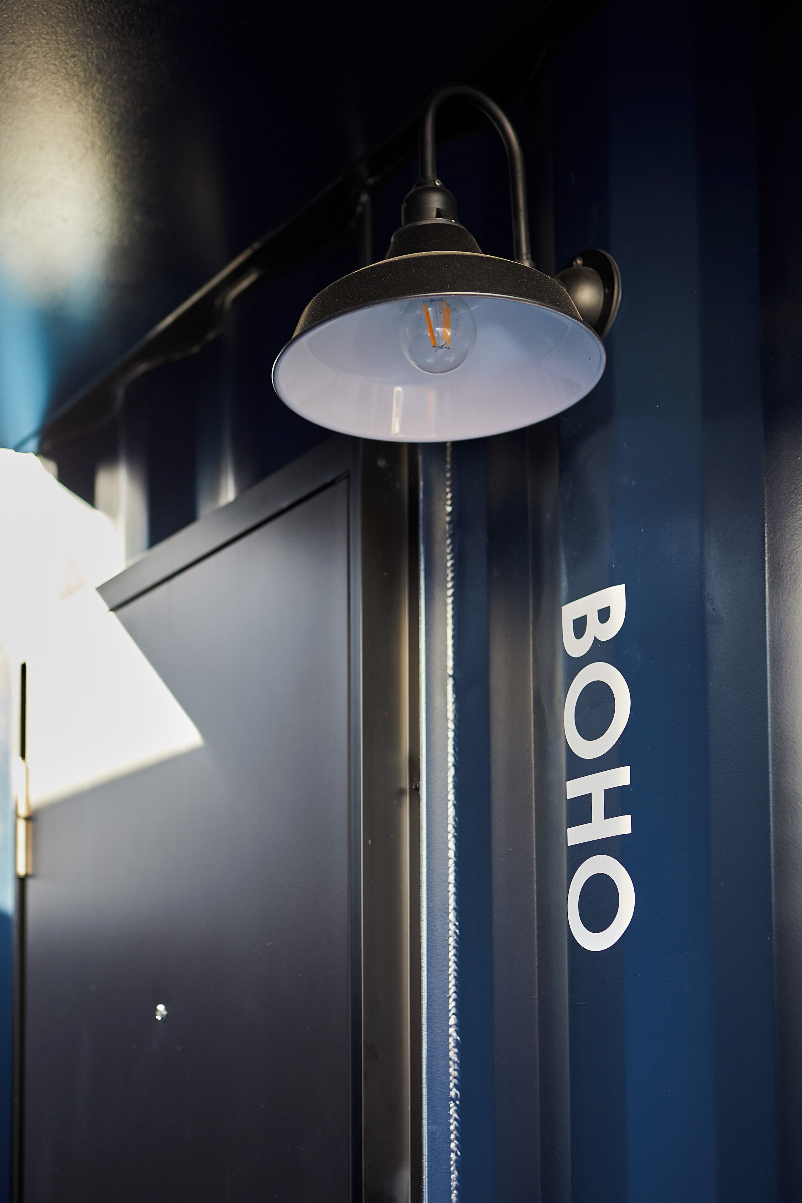 A modern industrial-style room with a large, dark blue wall and a metallic structure labeled "BOHO".