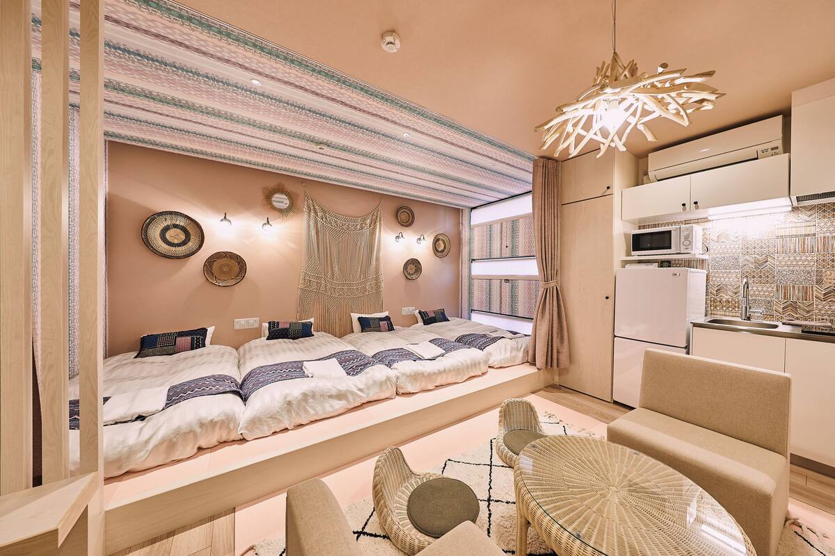 A modern bedroom with a large bed, bedside tables, and a view of the kitchen.