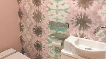 A bathroom with a toilet, sink, and a toilet paper holder.