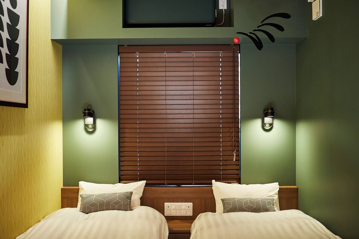 A hotel room with a wooden headboard, two bedside tables with lamps, and a television mounted above the headboard.