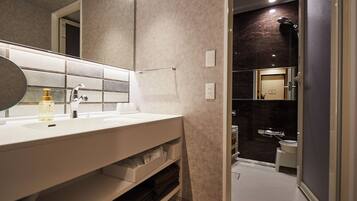 A modern bathroom with a large mirror, white sink, and a shower area.