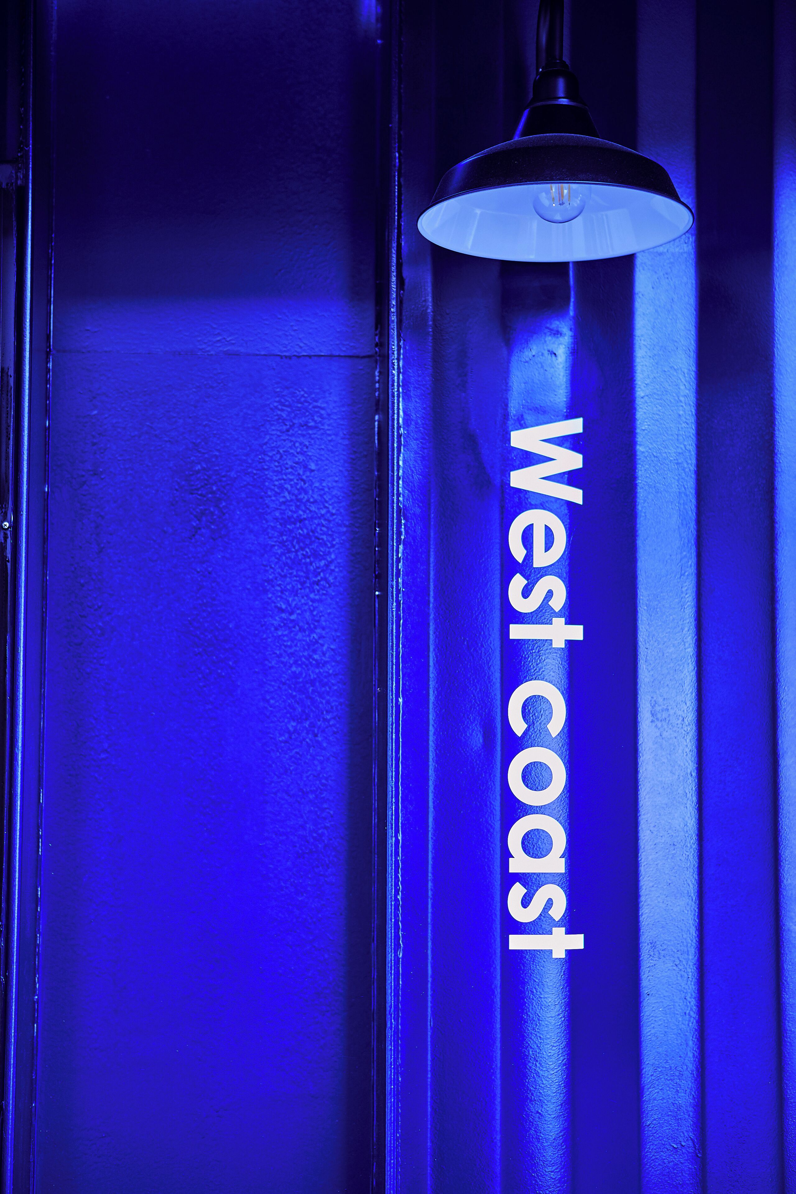A vertical sign with the text "West coast" in white letters on a blue background.