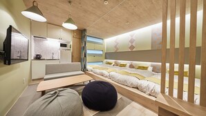 A compact bedroom with a bed, sofa, and a small kitchenette. - TORACO konohana (Osaka)