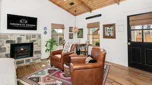 A cozy living room with leather chairs, a fireplace, and a sign for 'Absolute Charm Luxury Accommodations'.