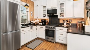 A modern kitchen with white cabinets, stainless steel appliances, and wooden accents.