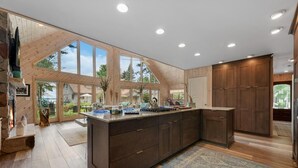 Una cocina moderna con una isla grande, armarios de madera y vistas al exterior.