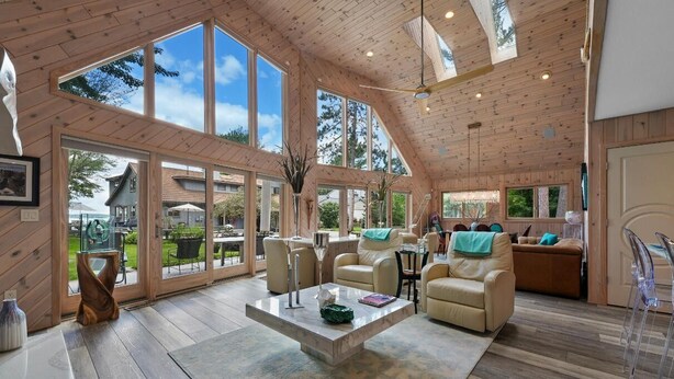 Un interior amplio con ventanas grandes, pisos de madera y una variedad de zonas de estar, incluyendo sofás y sillones.