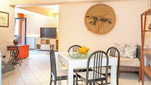 A modern living room with a dining area, a TV, and a decorative wall piece. - Etna, Mare e Verde - Open Space (Mascali)