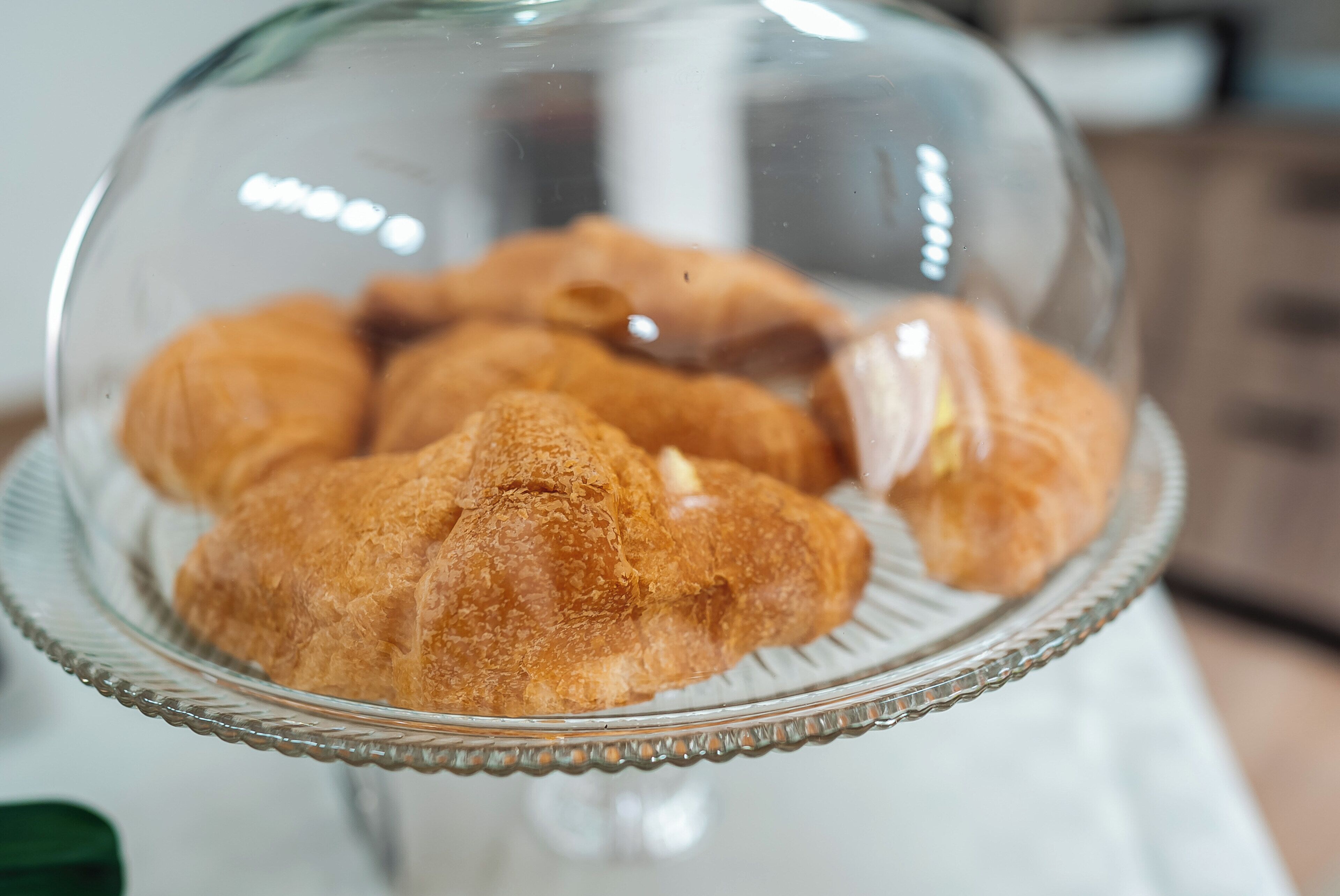 A glass dome covering a plate with croissants.