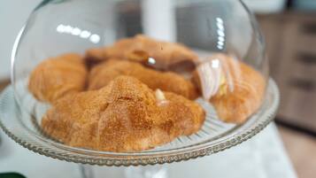 A glass dome covering a plate with croissants.
