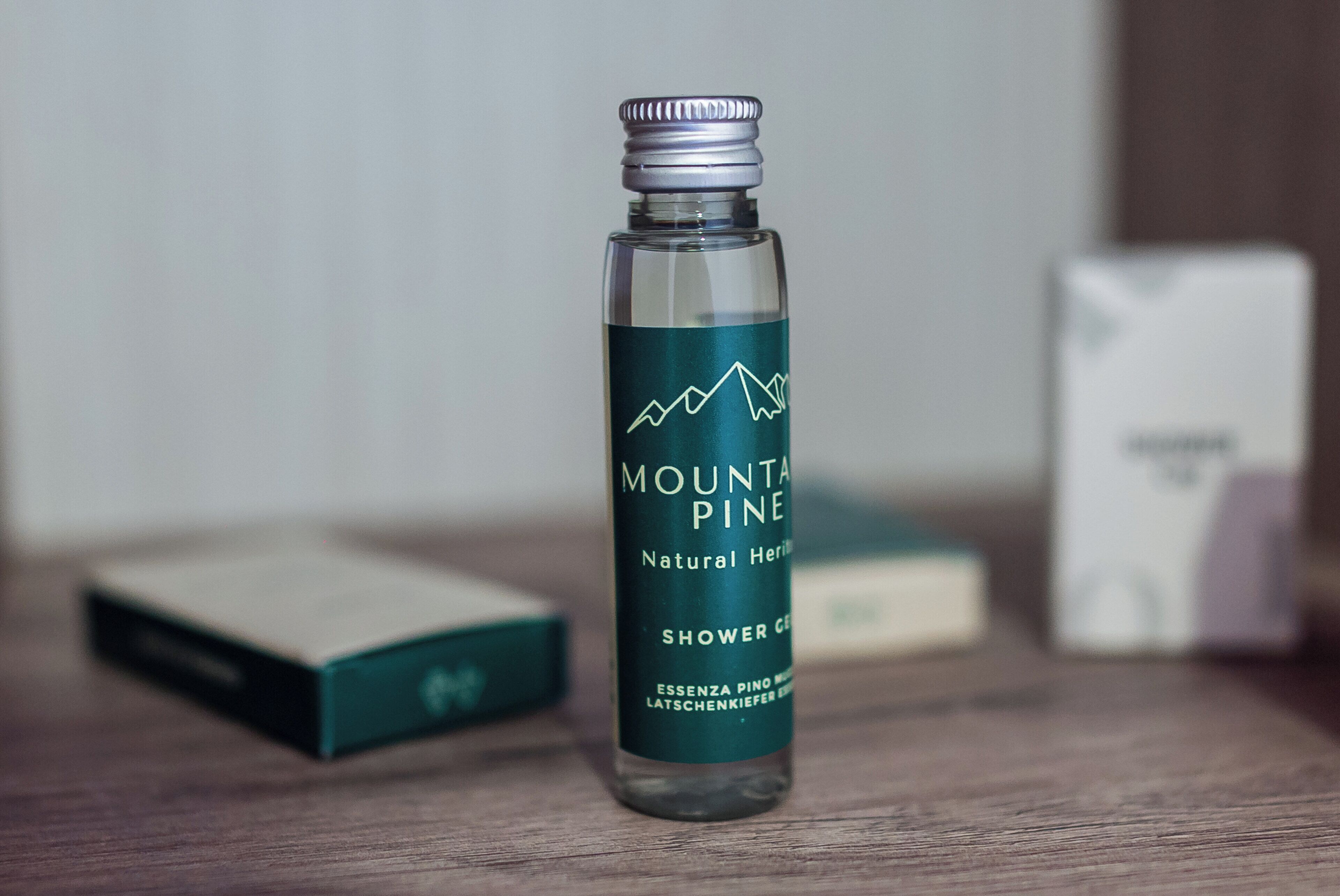 Una botella de gel de ducha Mountain Pine sobre una superficie de madera con fondo desenfocado.