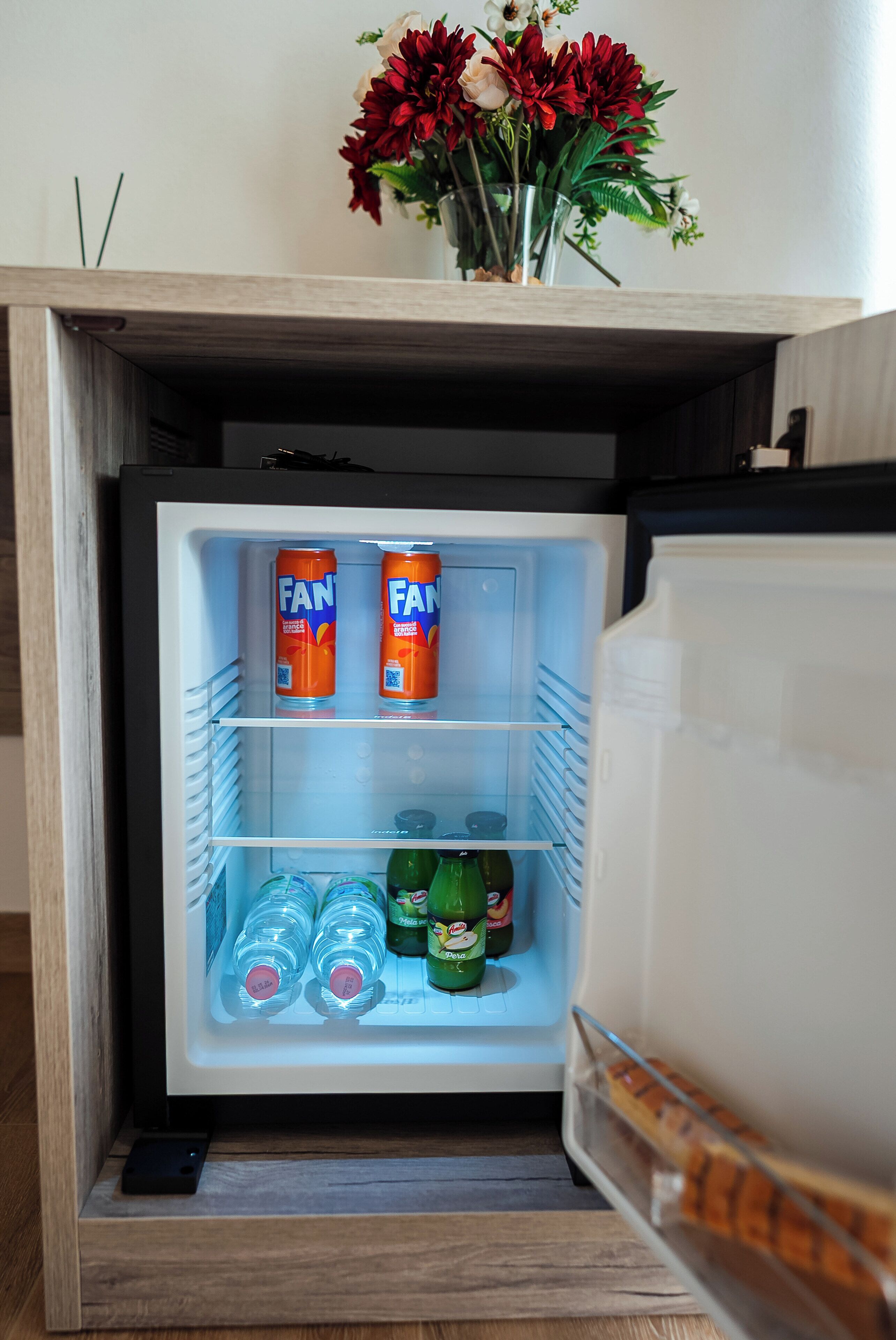 A mini-fridge with two cans of Fanta, several bottles of Sprite, and a bottle of Pepsi.