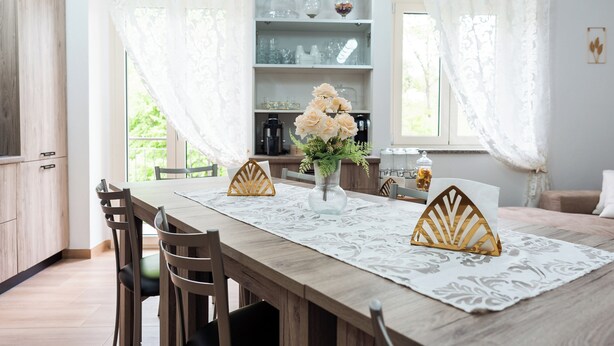 Un comedor con una mesa de madera, sillas y un florero con flores.
