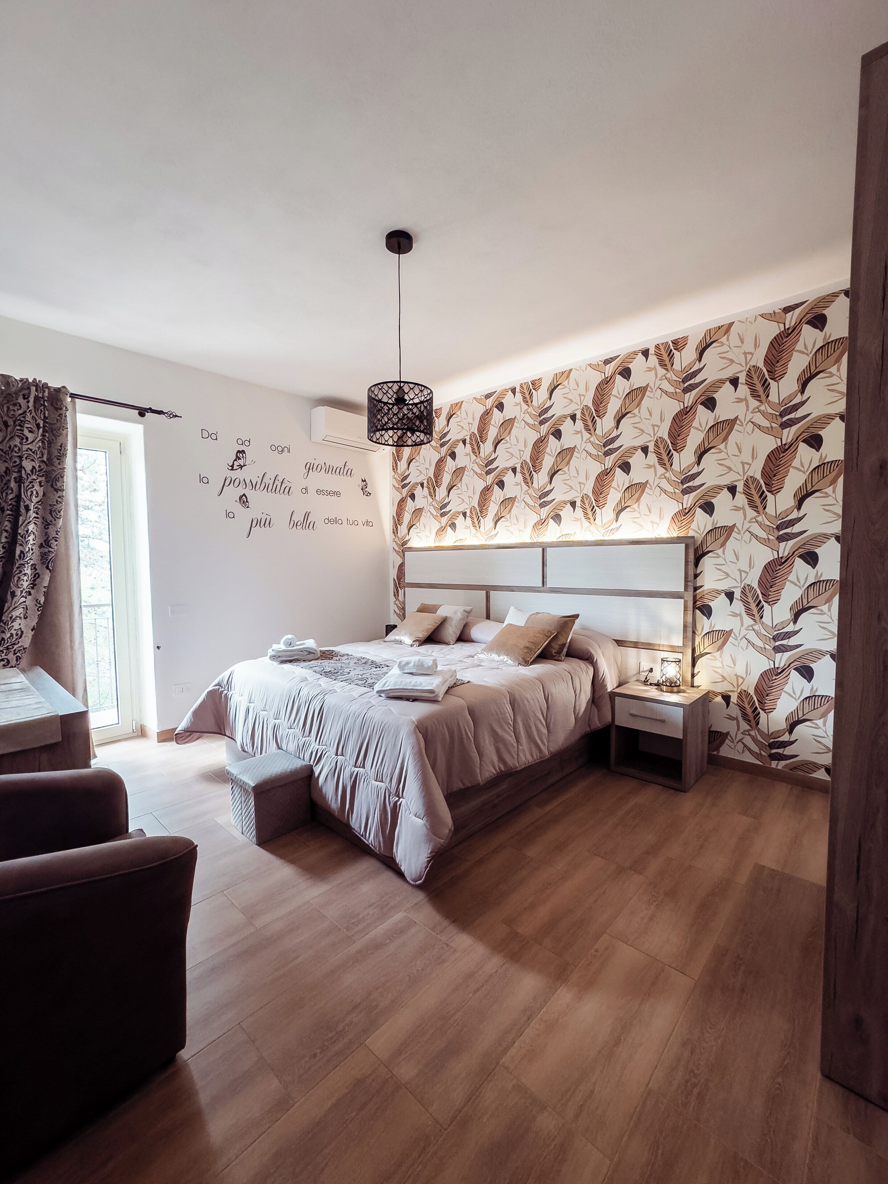 Un dormitorio con cama, mesita de noche y pared decorada con un diseño de hojas.