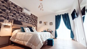 Un dormitorio con cama, mesitas de noche, un espejo, cómoda y ventana con cortinas.