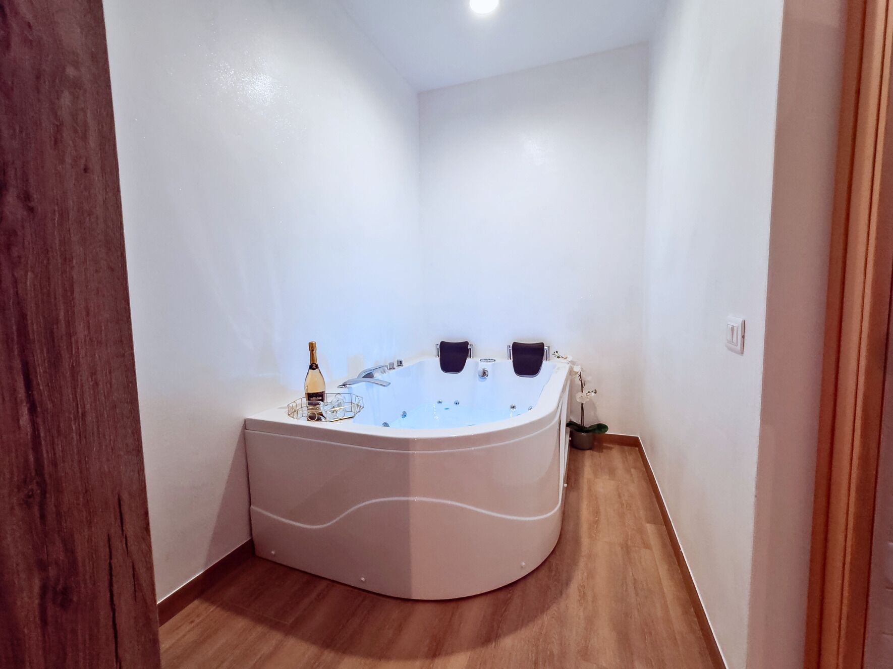 Ein modernes Badezimmer mit einer freistehenden Badewanne, einer Champagnerflasche und einem kleinen Blumentopf.