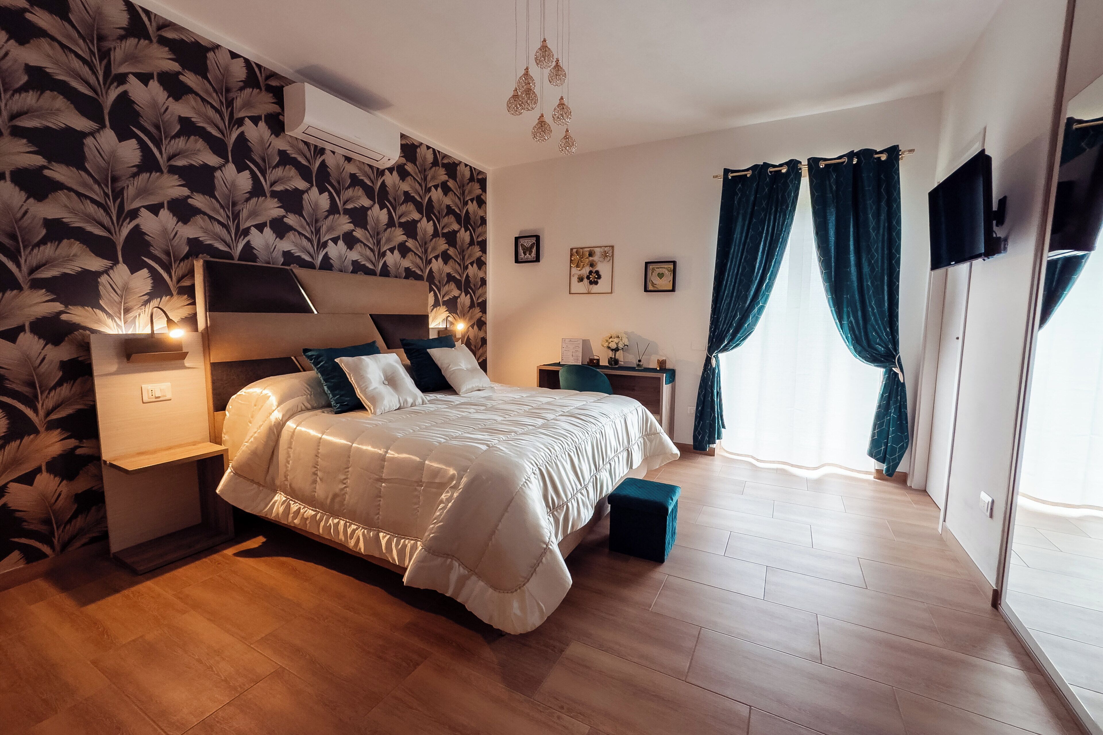 Un dormitorio con cama, mesitas de noche, espejo y ventana con cortinas.