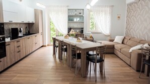 Una cocina moderna con armarios de madera, una mesa de comedor con sillas y un sofá en una habitación luminosa con ventanas amplias.