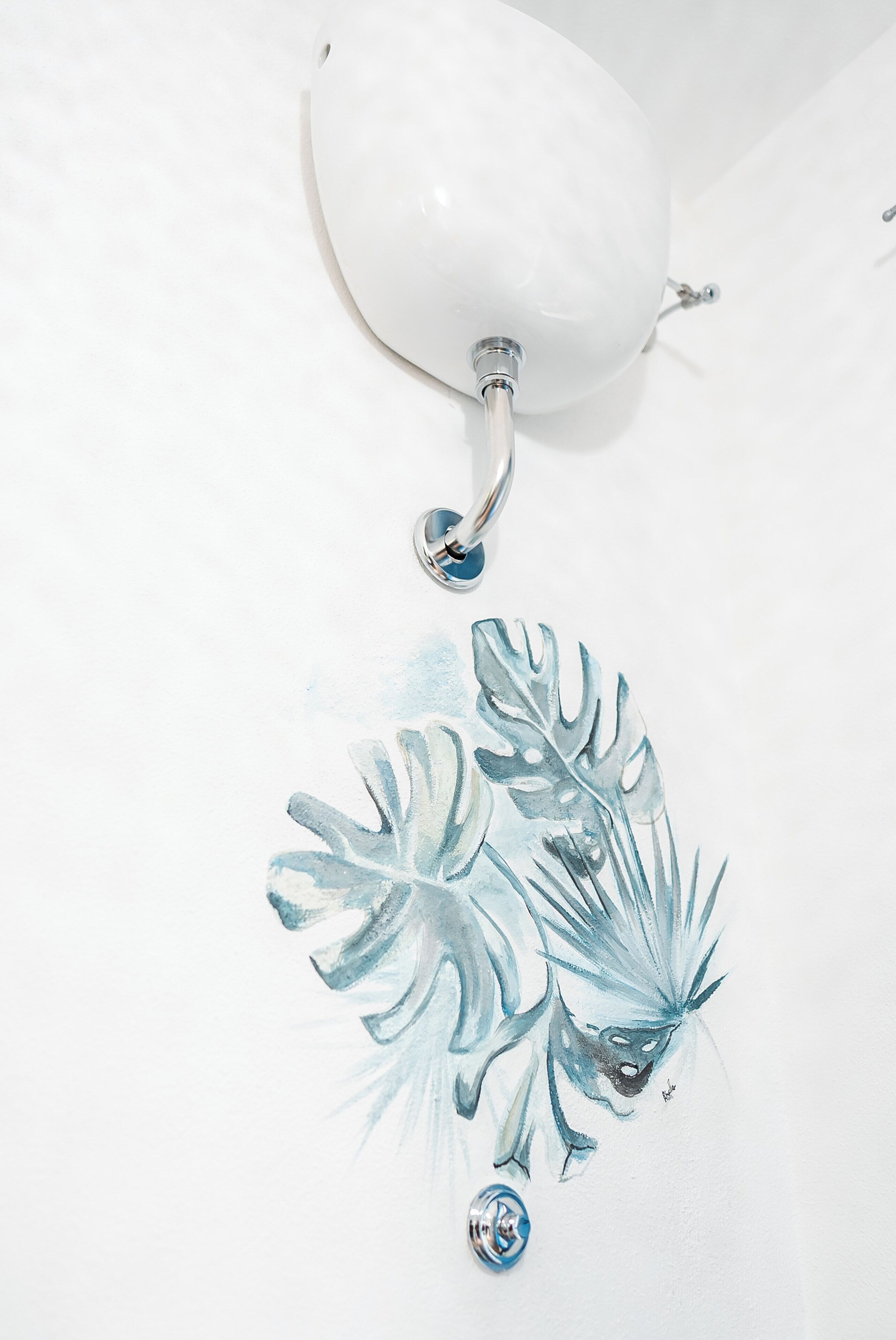 Pared blanca con una lámpara blanca en el techo y una decoración de gota de agua azul.