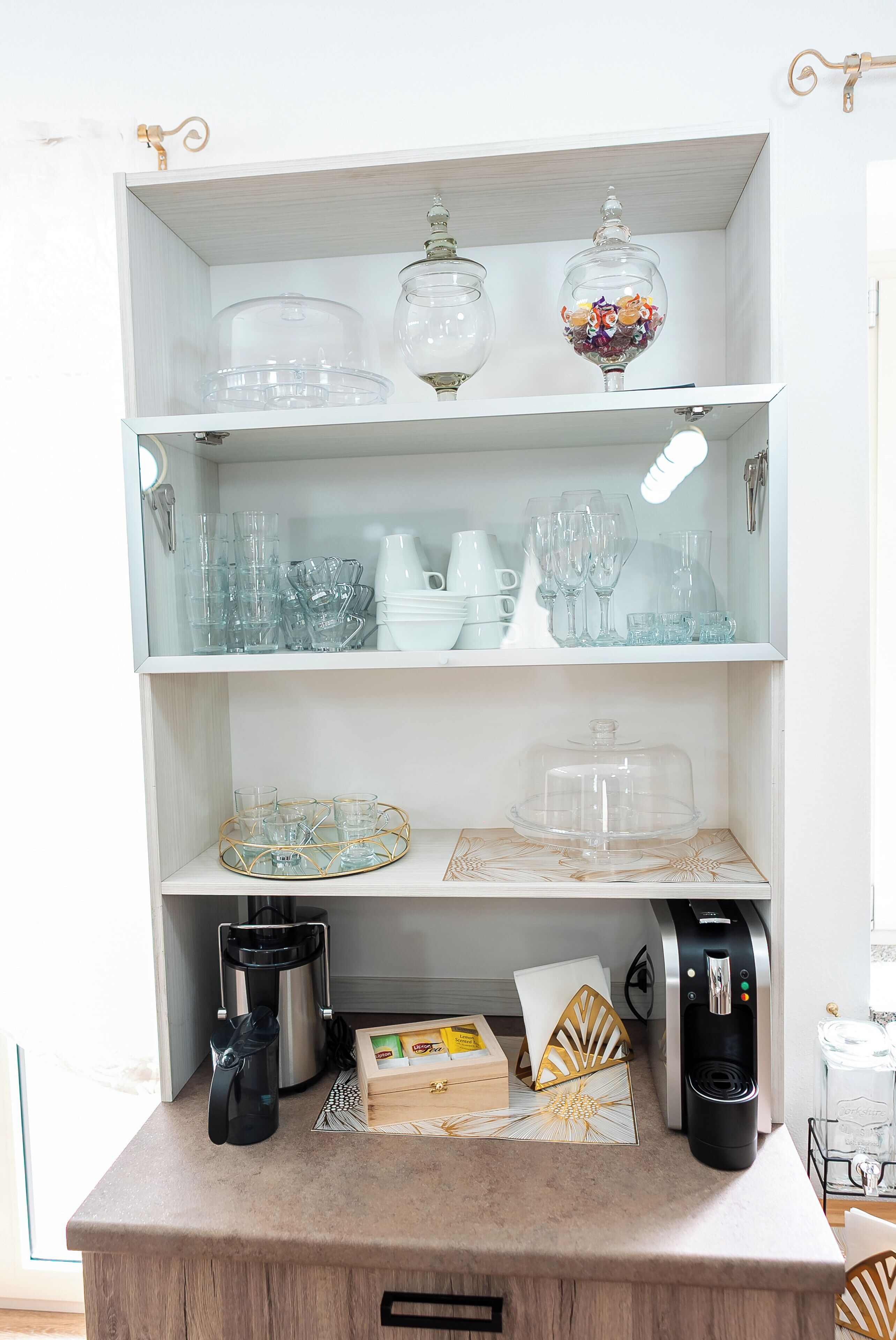 Een keuken met een koffiezetapparaat, een waterkoker en een waterdispenser op het aanrecht.