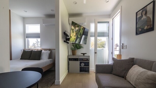 A modern room with a bed, sofa, TV, and a small table.