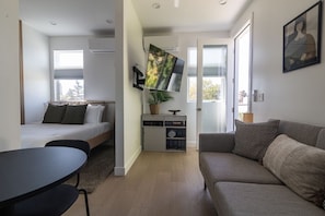 Una camera moderna con un letto, un divano, una TV e un tavolino.