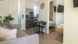 A modern apartment with a kitchenette, a dining area, a living room with a sofa, and a bed.