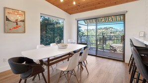 A dining area with a white table, modern chairs, and a view of a balcony with outdoor furniture. - Surf Shack at Lake Nacimiento with Private Slip! (Bradley)